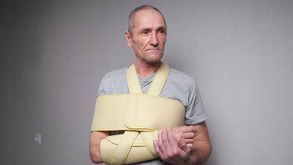 Senior Man with Fixating Bandage Checks Fingers and Joints