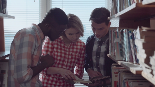 People Discussing Books Between Stacks