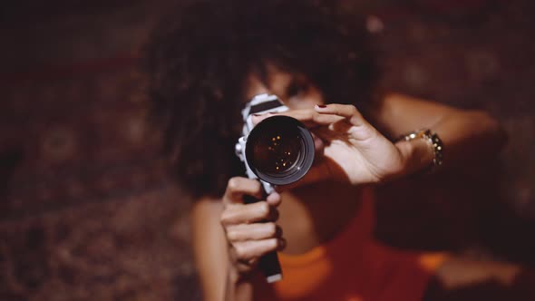 Woman With Afro Hair In Orange Dress Using Vintage 8Mm Camera