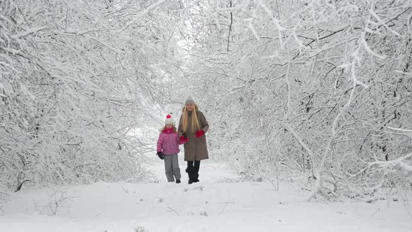 Happy mom plays with her daughter in a beautiful winter park