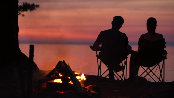 Couple Is Sitting Near Campfire at Night.