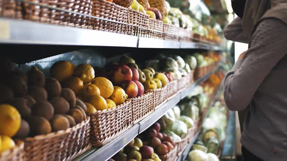 Close Up Shot of Young Beautiful Muslim Woman in Hijab and Protective Mask Choosing Fruits in the