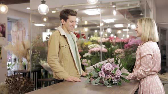 Handsome Young Man Buying Flowers In Shop. Small Talk. Smile.