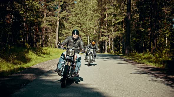 Two Motorcyclists Riding on the Road in the Forest