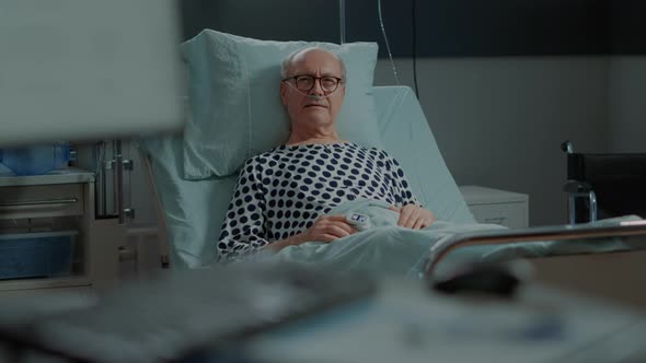 Portrait of Elder Patient Sitting in Hospital Ward Bed