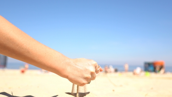 Sand Pouring From the Hands of a Woman on the Beach.