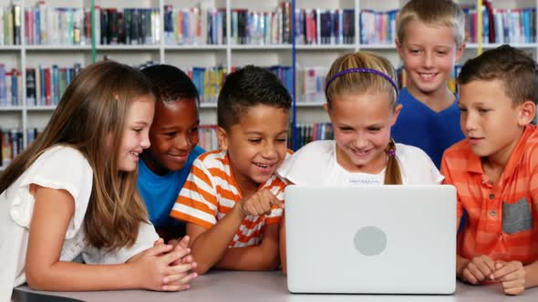 School kids using laptop in library