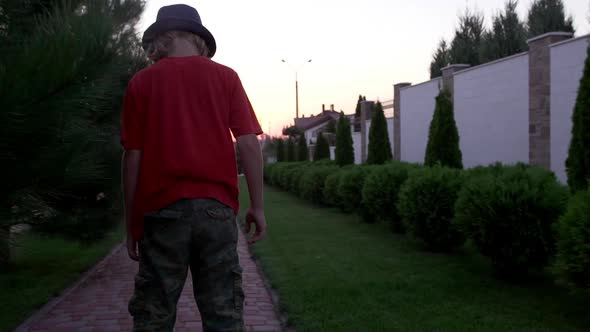 Young Caucasian Boy in Hat and Red Tshirt Driving Gyroscooter Through the Alley in Slowmotion