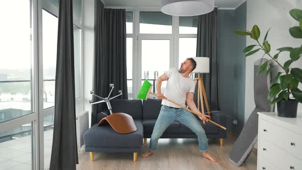 Man Does the Cleaning and Imagines Himself a Rock Star Plays the Broom Like a Guitar