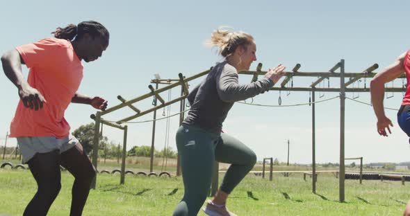 Diverse fit group running through tyres on obstacle course in the sun