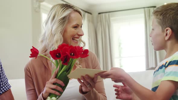 Son offering bunch of flowers to his mother in living room