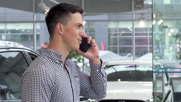 Excited Man Smiling, Holding Car Keys at the Dealership, Talking on the Phone