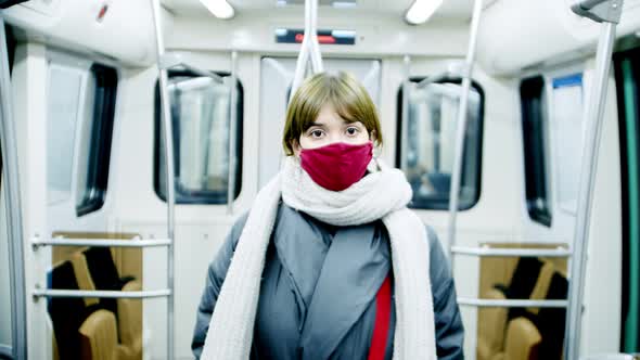 a Woman in a Subway Car Wearing a Mask Looks at the Camera