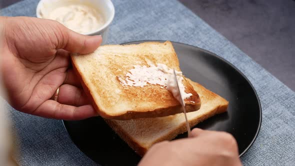 Women Hand Spreading Low Fact Cheese Cream Spread on a Bread