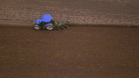 Agricultural Work in the Field, Two Blue Tractors Plow the Land