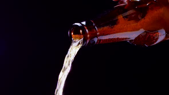 Beer Is Poured From Dark Glass Bottle and Ends. Closeup