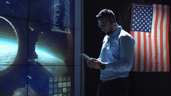 Man with Tablet in Mission Control Center. Elements of This Image Furnished By NASA.