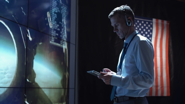 Man with Tablet in Mission Control Center. Elements of This Image Furnished By NASA.