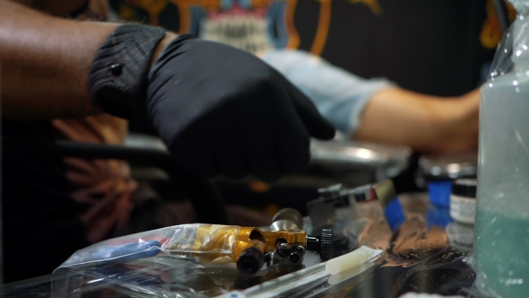 Tattoo Artist Dipping the Machine Needle Into Disposable Ink Cup. Man Working on Black Gloves