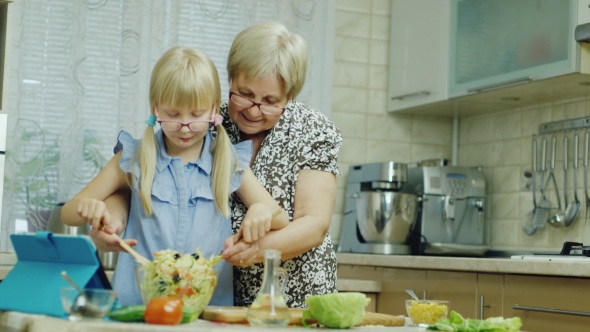  Girl of 6 Years Together with the Grandmother Do a Salad in Kitchen