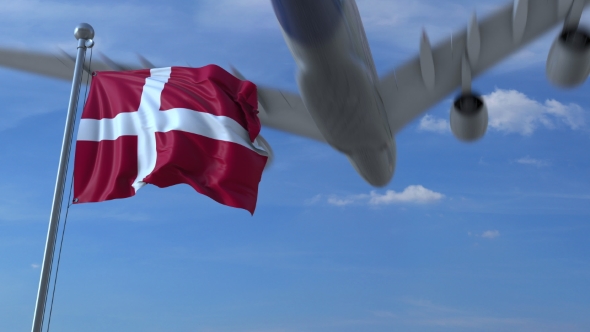 Commercial Airplane Landing Behind Waving Danish Flag