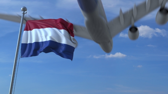 Commercial Airplane Landing Behind Waving Dutch Flag