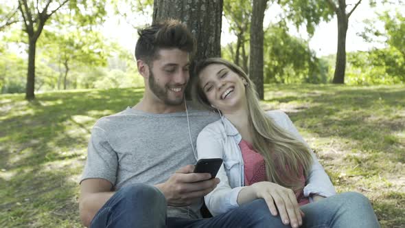 Young couple listening to music on smartphone