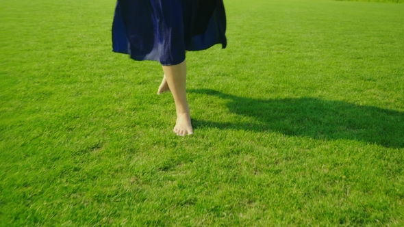 Barefooted Female Legs Walking on Green Grass