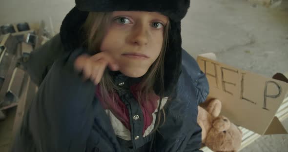 Close-up Face of a Sick Homeless Caucasian Girl with Grey Eyes Looking at the Camera and Around