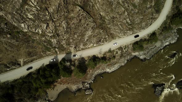 A Convoy of Passenger Cars Moves Along the Mountainous Terrain