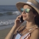 The Girl Is Talking on the Phone While Sitting on the Beach - VideoHive Item for Sale