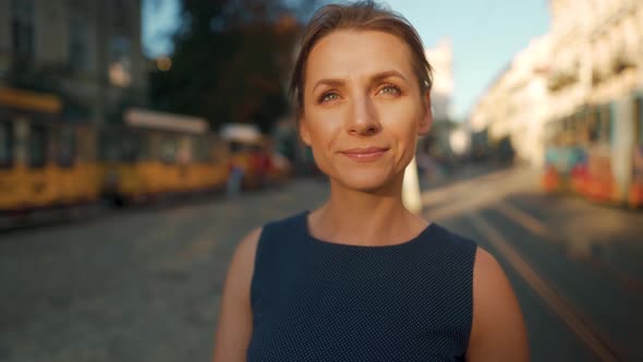 Portrait of a Woman Who Stands in the Middle of a City Square and Puts on Glasses