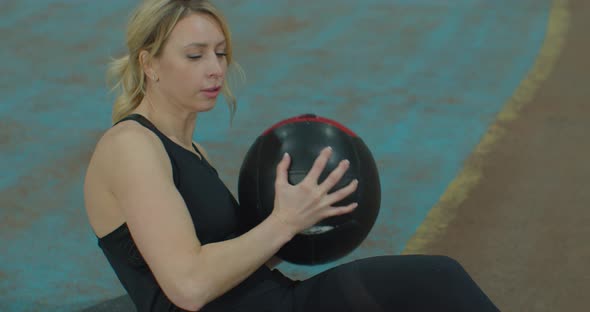 Young Athletic Woman Doing Abdominal Press Exercise Works Hands and Feet Uses Ball Dressed in Black