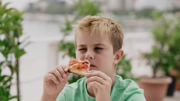 A Boy of 10 Years Eats Pizza with Pleasure