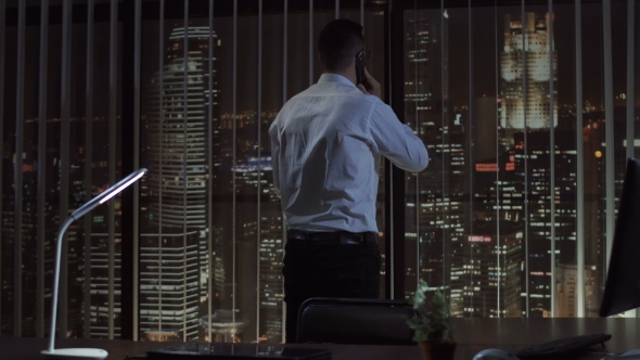 Man in Office Talking Phone at Night