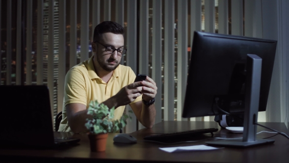 Man Using Phone in Office at Night