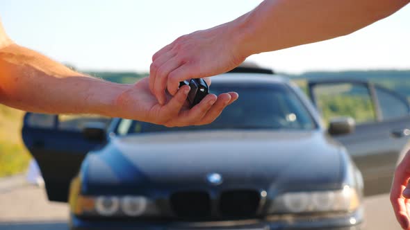 Unrecognizable Man Getting Car Key From Seller. Male Hands Giving Keys of Car To His Friend Outdoor