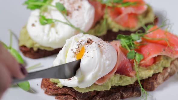 Toast with salmon, poached egg and avocado on white plate. 