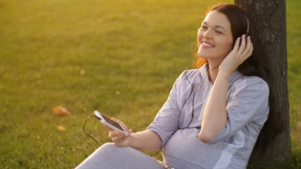 Pregnant Woman Listening To Music on Nature