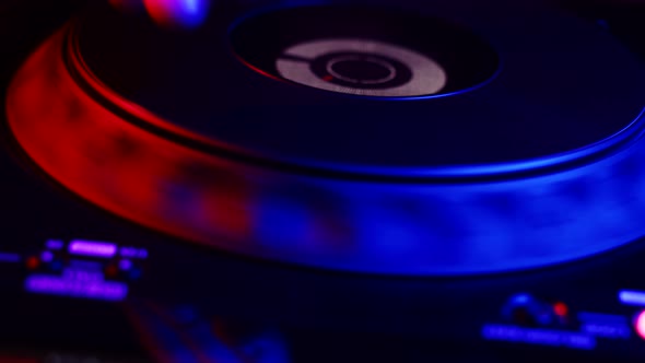 DJ's Hand Adjusts Rotating Jog on Digital Music Console in Neon Light in Nightclub Closeup