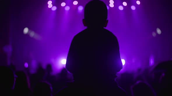 Silhouette Fan Kid Boy on Father Shoulders Enjoying Listening to Artist During Concert at Night