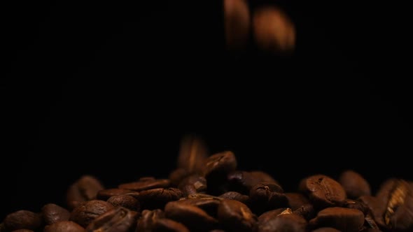 Slow motion of roasted coffee beans falling. Organic coffee seeds.