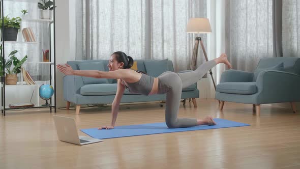 Athletic Female Doing Yoga In Balancing Table Pose On The Mat At Home With Online Coach Via Laptop