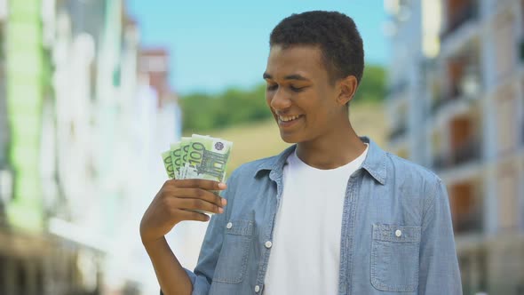 Glad Mixed-Race Young Male Showing Euros Bunch and Smiling, First Salary Finance