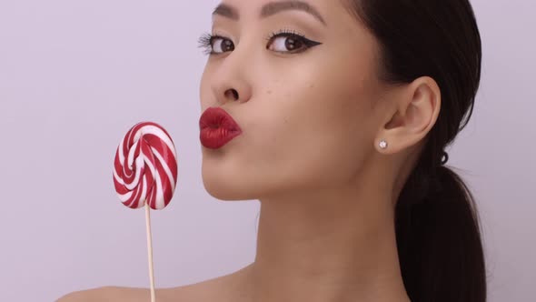 Fashion Portrait of Asian Woman with Lollipop in Studio