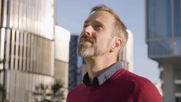 A Middleaged Handsome Caucasian Man Looks Around in an Urban Area  Office Buildings