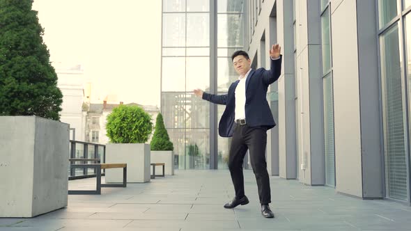 Cheerful happy asian business man dancing walk the corridor backdrop a modern office 