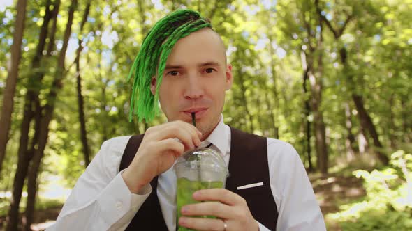 Young Man with Dreadlocks Drinking Refreshing Lemonade in Forest Park