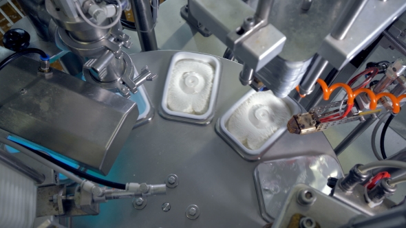 A Round Table with Robotic Equipment for Cheese Packing.