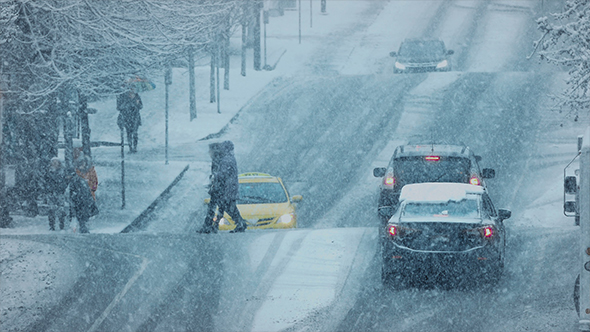 People Crossing Busy Road In Snowstorm